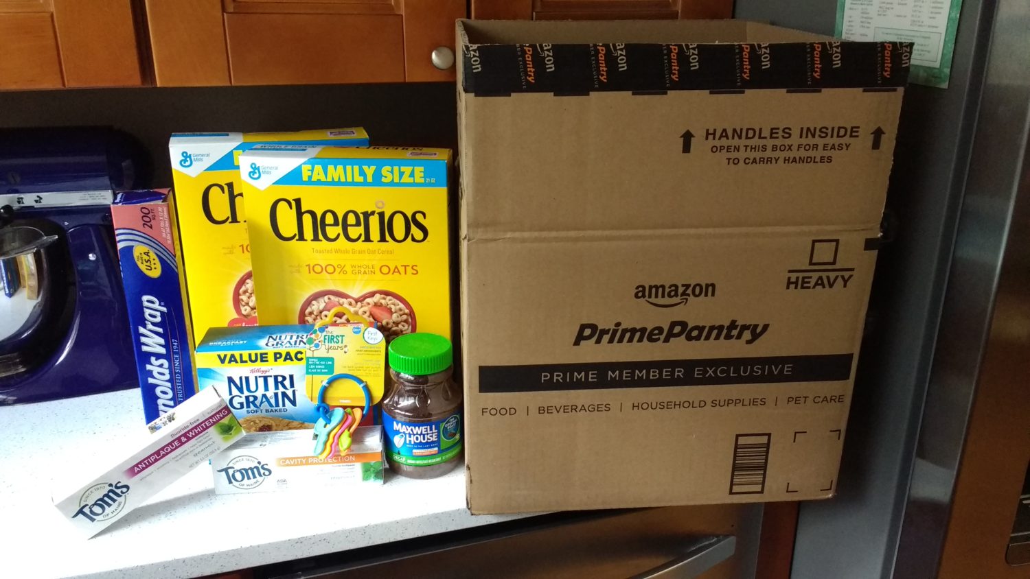 Amazon Prime Pantry box with Cheerios, Reynolds Wrap, Tom's of Maine, Maxwell House, Nutri-Grain, and teether keys